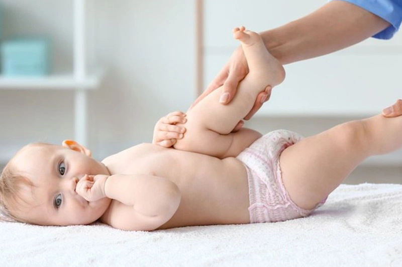 نوزادی که روی تخت دراز کشیده و کایروپراکتر در حال انجام درمان است