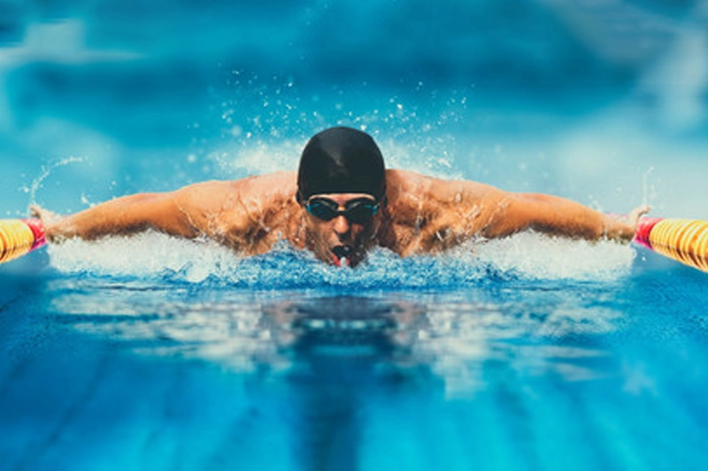 شناگر حرفه‌ای داخل استخر، در حال شنا در مسیر مسابقه‌ای.