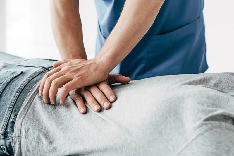 مردی به شکم دراز کشیده و کایروپراکتور در حال انجام منیپولیشن ستون فقرات با فشار دقیق و کنترلشده است.