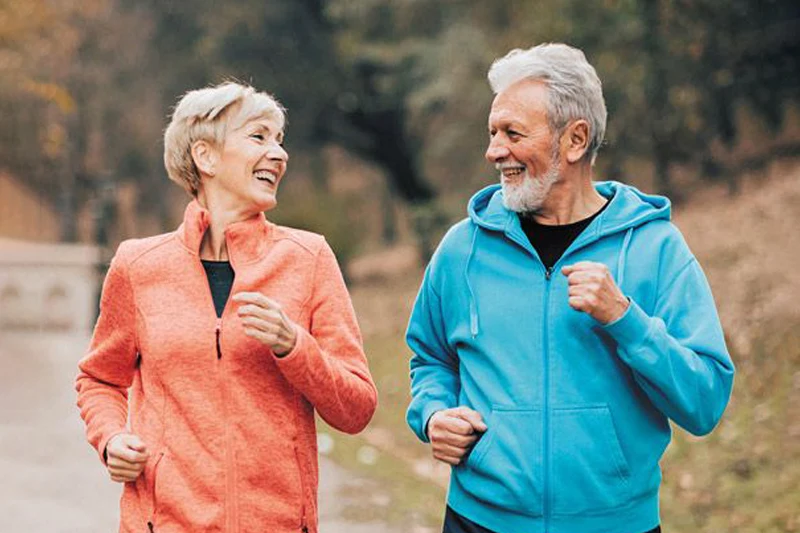 زوج سالمند با لباس ورزشی که بدون درد مفاصل با خوشحالی کنار هم می‌دوند