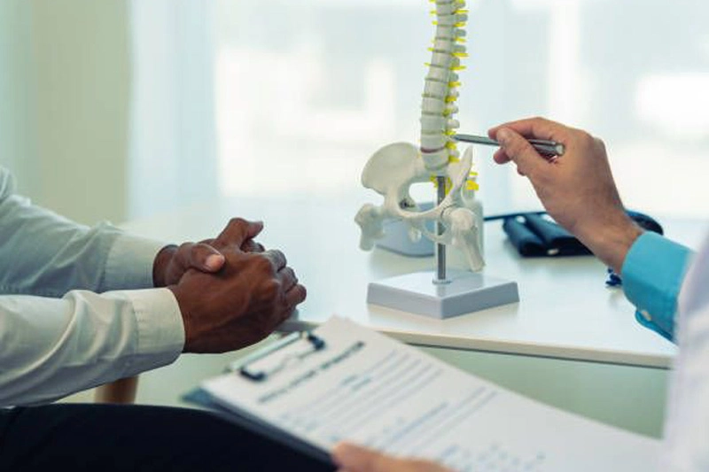 دکتر کایروپراکتیک در حال توضیح با استفاده از مدل آموزشی ستون فقرات درباره منیپولیشن و برنامه درمانی کامل.