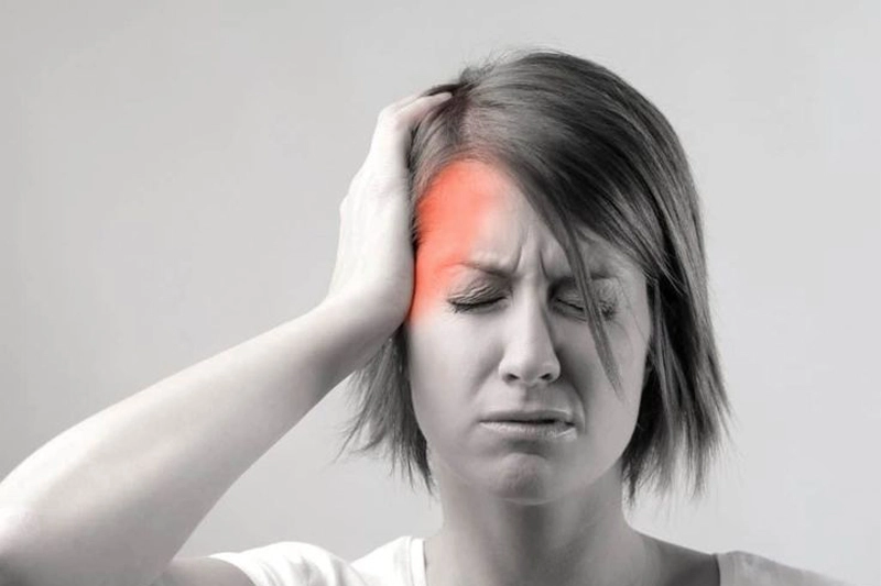 زنی که از میگرن رنج می‌برد و یک طرف سرش را نگه داشته است. 