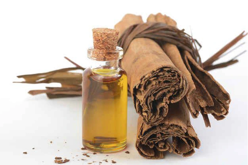 چند رول دارچین و بطری روغن، قابل استفاده برای ماساژ موضعی و افزایش گردش خون