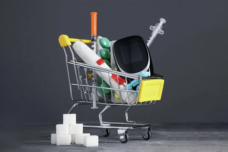 سرنگ انسولین، گلوکومتر و قرصهای دیابت روی کارت فروشگاه با مکعب قند کنار آن