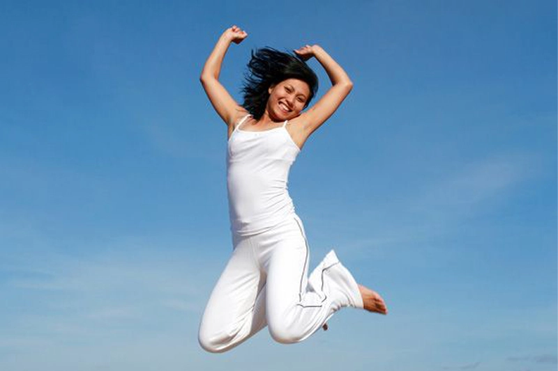 زنی پرانرژی که با خوشحالی در هوا می‌پرد