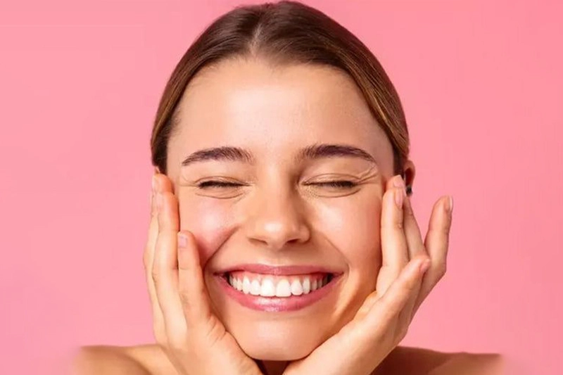 زنی با پوست سالم و درخشان که با خوشحالی لبخند می‌زند
