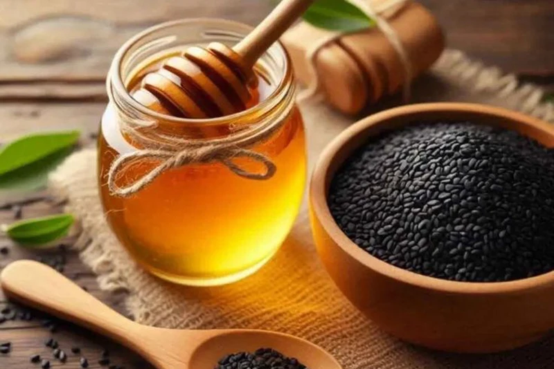 شیشه عسل با قاشق عسل و کاسه‌ای حاوی سیاه‌دانه کنار آن، ترکیب سنتی «دوسین» برای دفع بلغم 