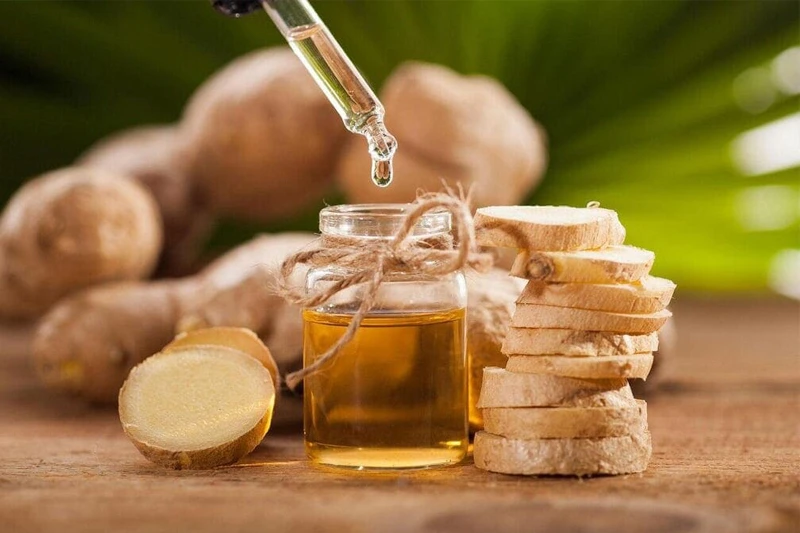 گیاه زنجبیل کامل و خردشده کنار بطری روغن حامل، آماده برای ماسک زنجبیل با روغن‌های حامل 